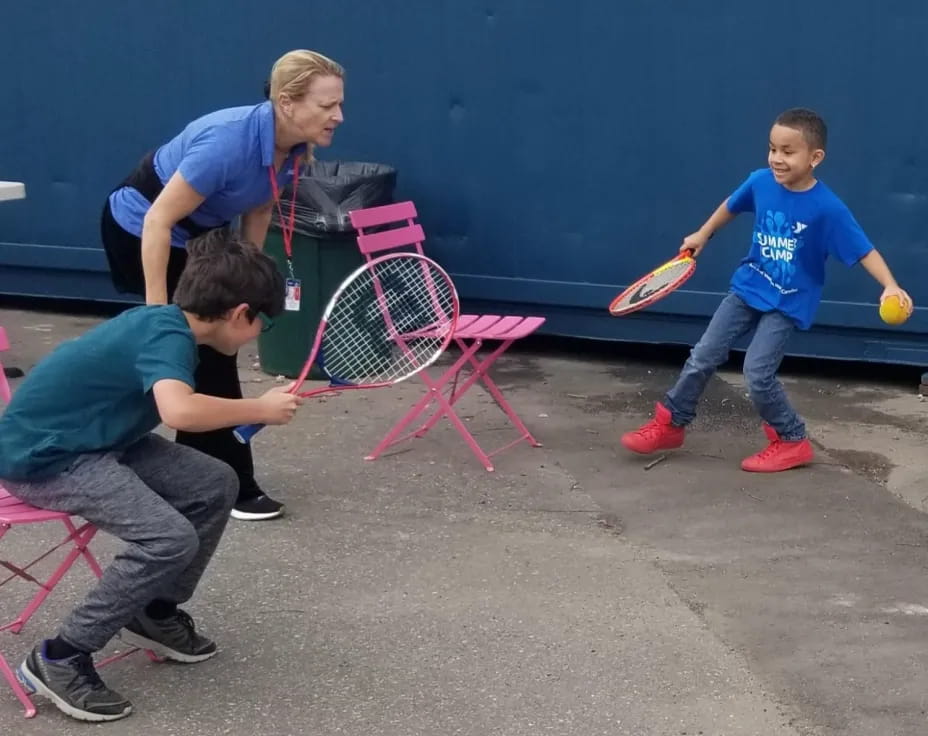 a person and kids playing with a ball and a racket