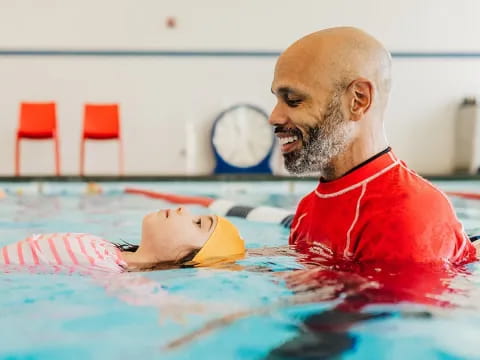 a person in a pool with a baby in it