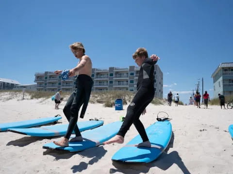 a couple of men stand on surfboards on a beach
