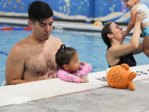 a man and woman with a baby in a pool