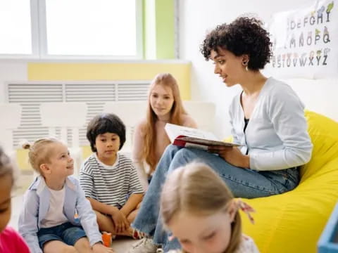 a person reading a book to a group of children