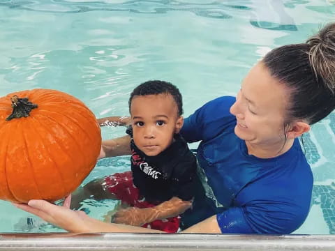 a man and a child in a pool with a ball