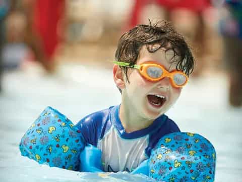 a boy in a pool wearing goggles and a swimsuit