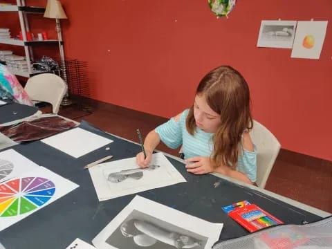 a girl sitting at a table writing on paper