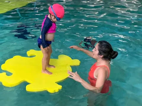 a couple of kids playing in the water with a yellow floaty