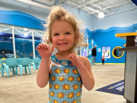 a girl smiling and holding her hand up