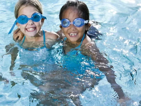 two kids wearing goggles and swimming in a pool