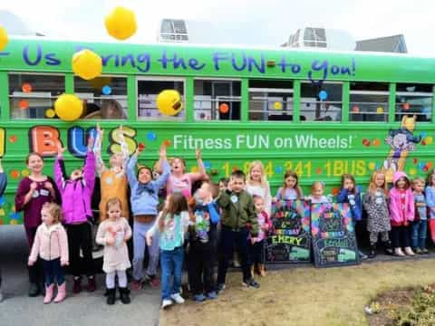 a group of children posing for a photo in front of a bus