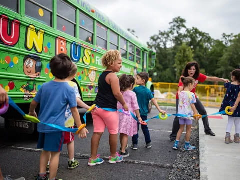a group of kids stand in front of a bus