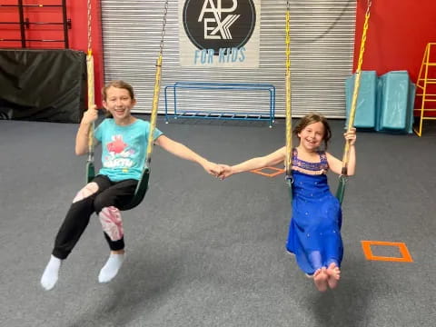 a couple of girls playing on a swing set