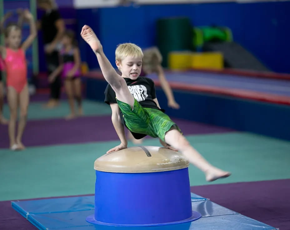 a boy jumping on a blue mat