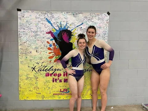 two women in swimsuits standing in front of a wall with a mural