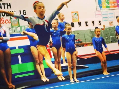 a group of women in leotards on a blue mat