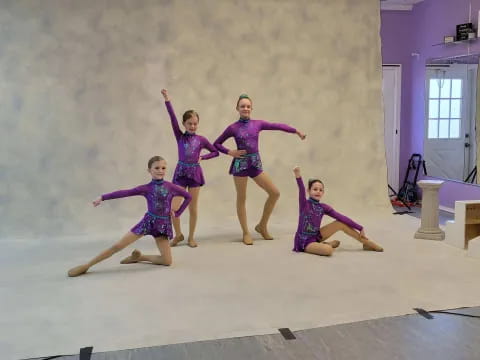 a group of girls in purple dresses jumping in the air