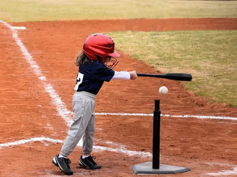 a little boy hitting a ball with a baseball bat