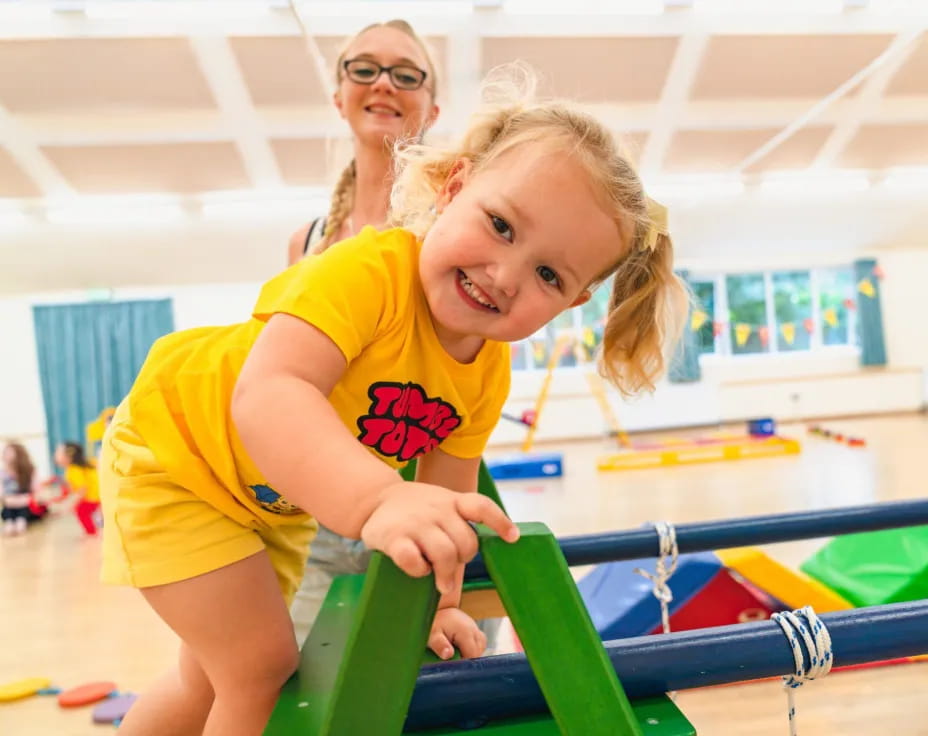 a girl smiling and playing on a toy train