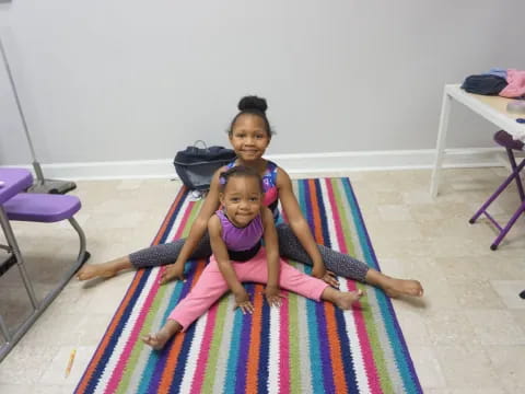 a person and a child sitting on a colorful mat in a room