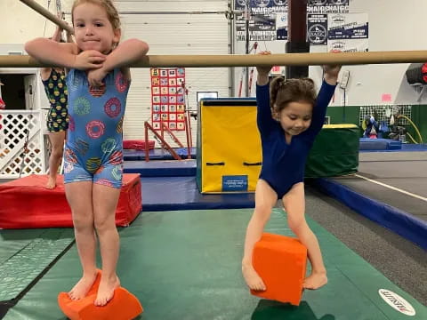 a couple of kids playing on a mat in a gym