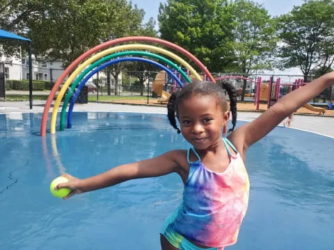 a girl in a pool with a rainbow in the background