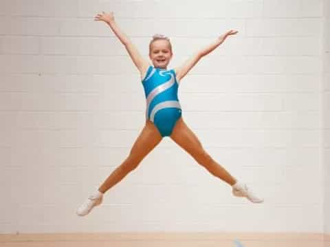 a woman in a leotard jumping in the air