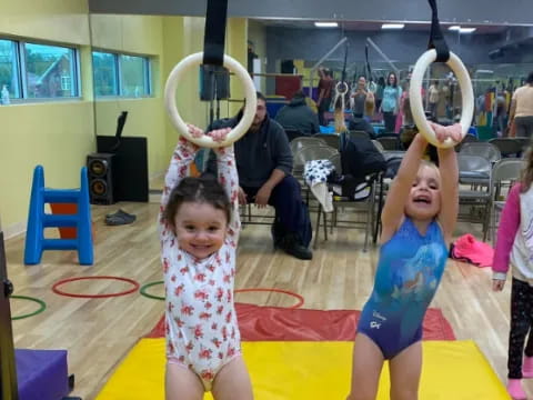 a couple of kids holding up large swords in a gym