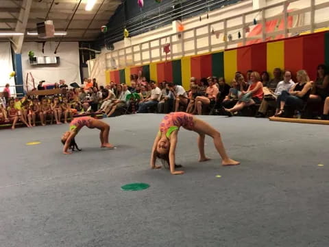 a couple of women playing frisbee in front of a crowd