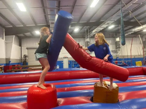 a woman standing on a red and blue tube in a gym