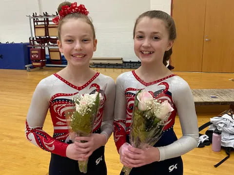 two girls wearing sashes and holding flowers