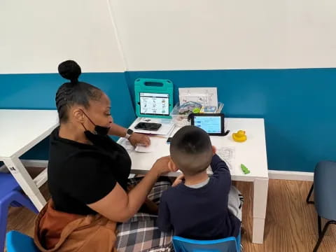 a man and a boy sitting at a table with computers