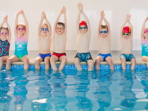 a group of children in swimsuits jumping into a pool
