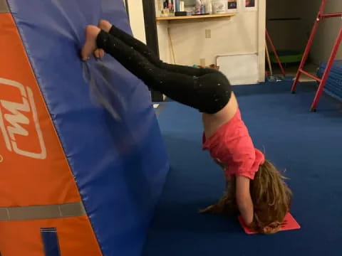 a girl doing a handstand on a mat