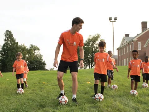 a person in orange shirt playing football with a group of kids