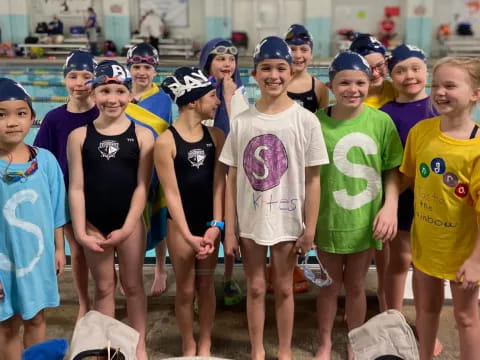 a group of people wearing swimsuits and standing in water