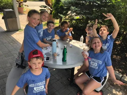 a group of kids sitting around a table with food and drinks