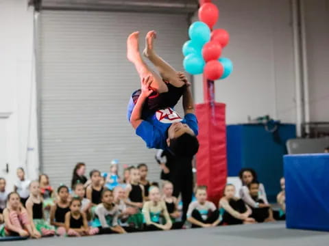 a person doing a handstand on a pole with balloons