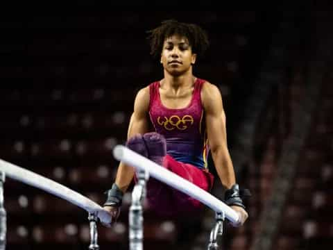 a person in a leotard jumping over a bar