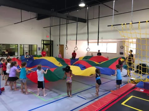 a group of children playing on a trampoline in a gym