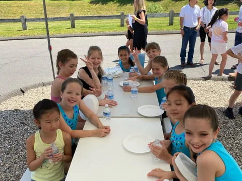 a group of children sitting at a table outside