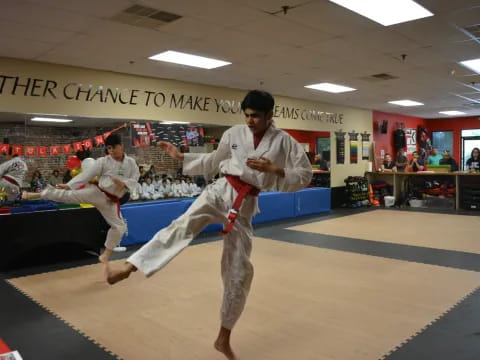 a man in a karate uniform kicking another man in the face