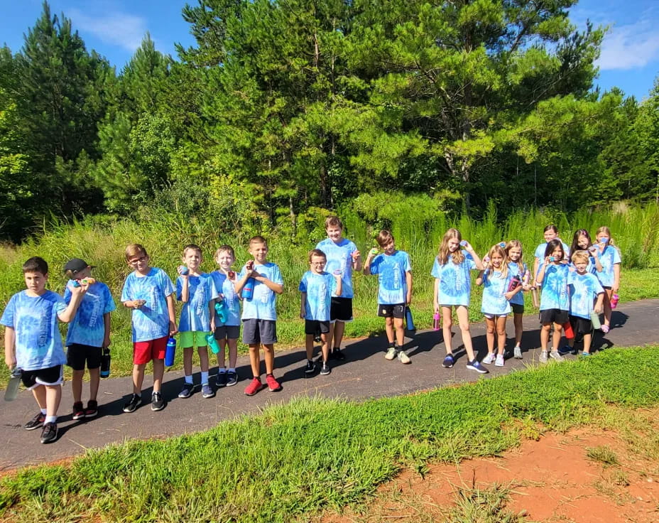 a group of people wearing matching t-shirts and running on a dirt road