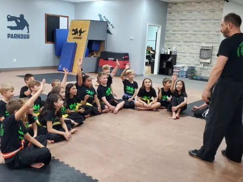 a person standing in front of a group of kids sitting on the floor
