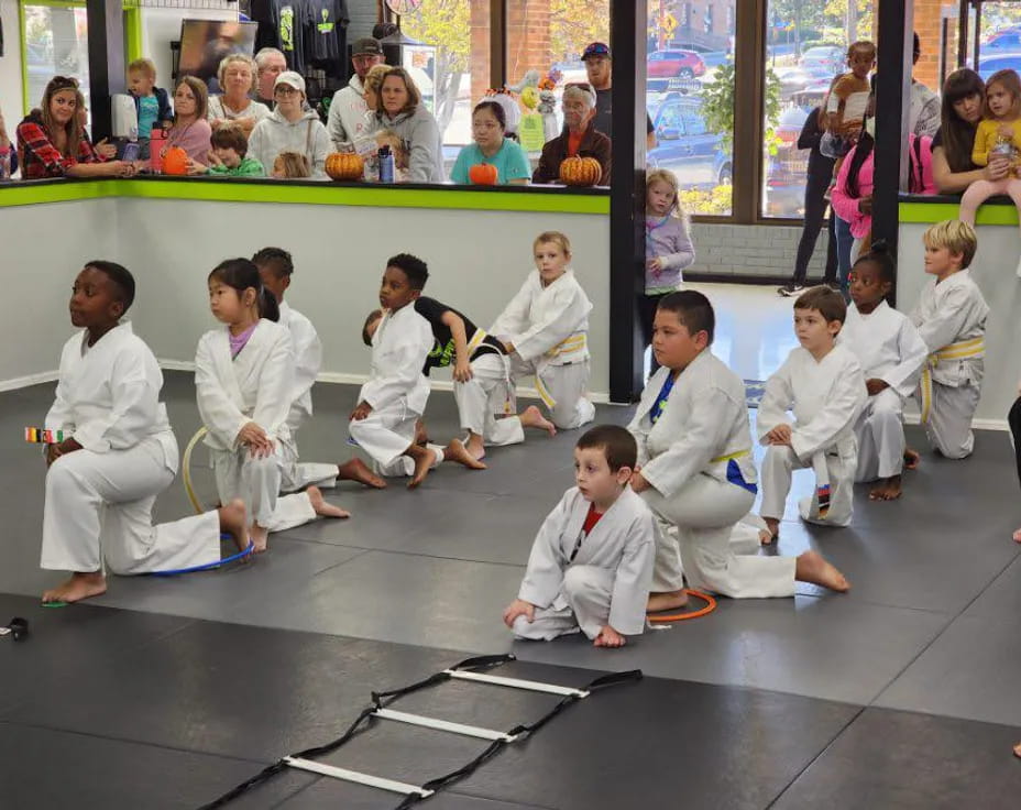 a group of people in white karate uniforms sitting on the floor