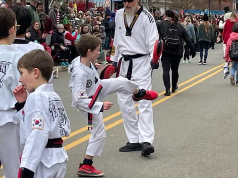 a group of people in white karate uniforms walking down a street