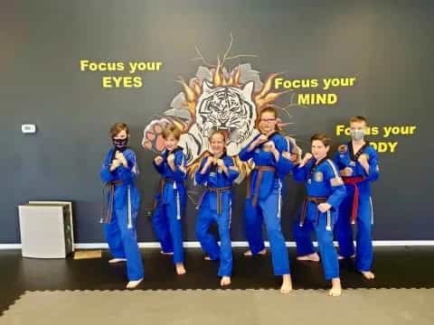 a group of people in blue karate uniforms standing in front of a blackboard