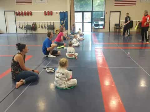 a group of people sitting on the floor in a gym