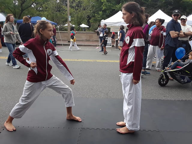 a couple of girls in red karate uniforms walking on a street