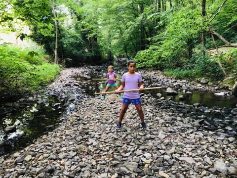 a person and a girl walking on a rocky path in the woods