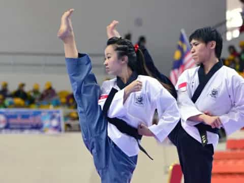 a man and a woman in karate uniforms with their arms up