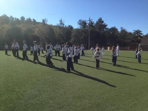a group of people in white uniforms holding swords on a grass field