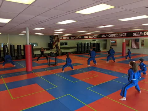 a group of people in blue uniforms on a mat in a gym